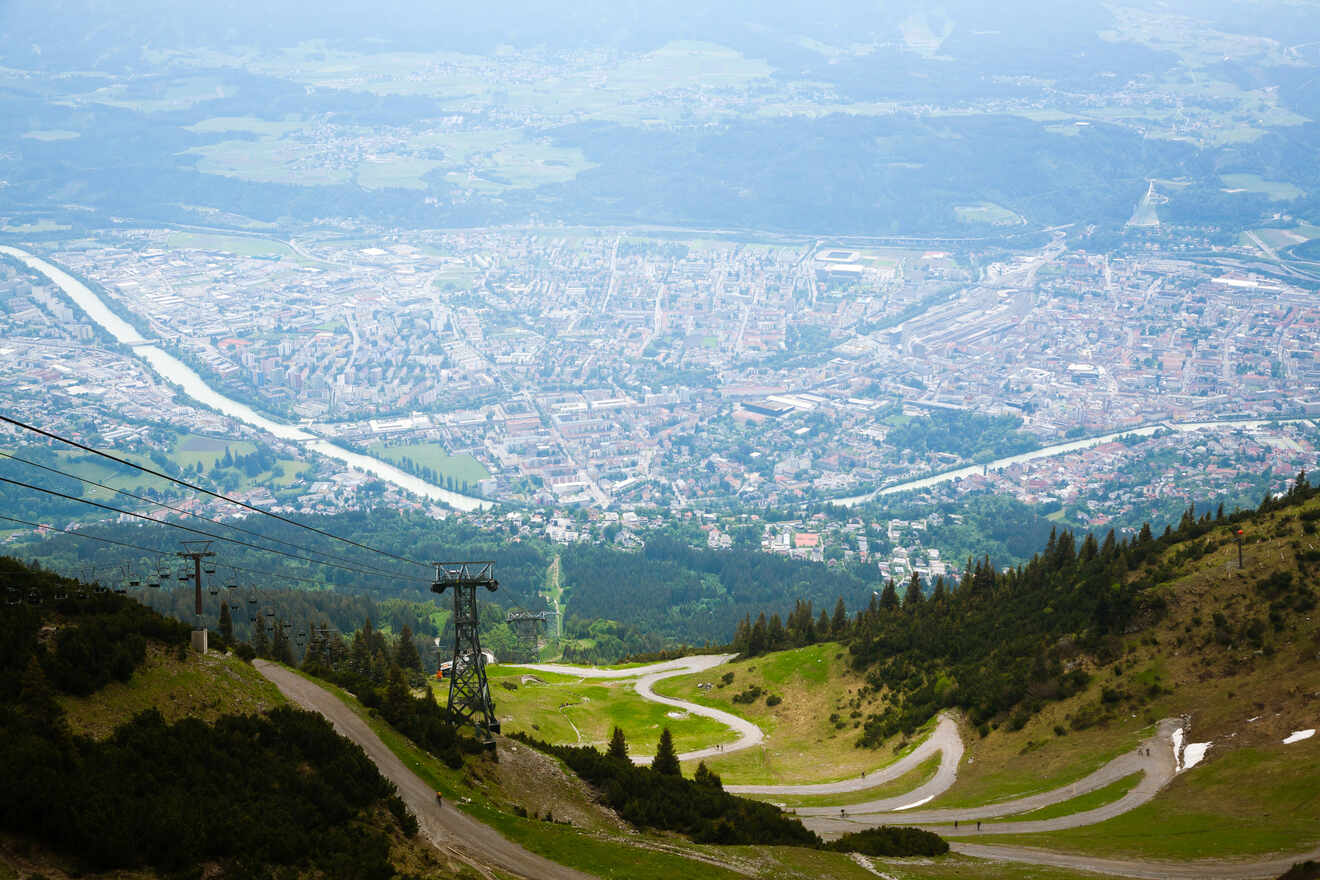 Aerial view of Innsbruck from the mountains, showcasing the sprawling city, winding river, and dense urban landscape